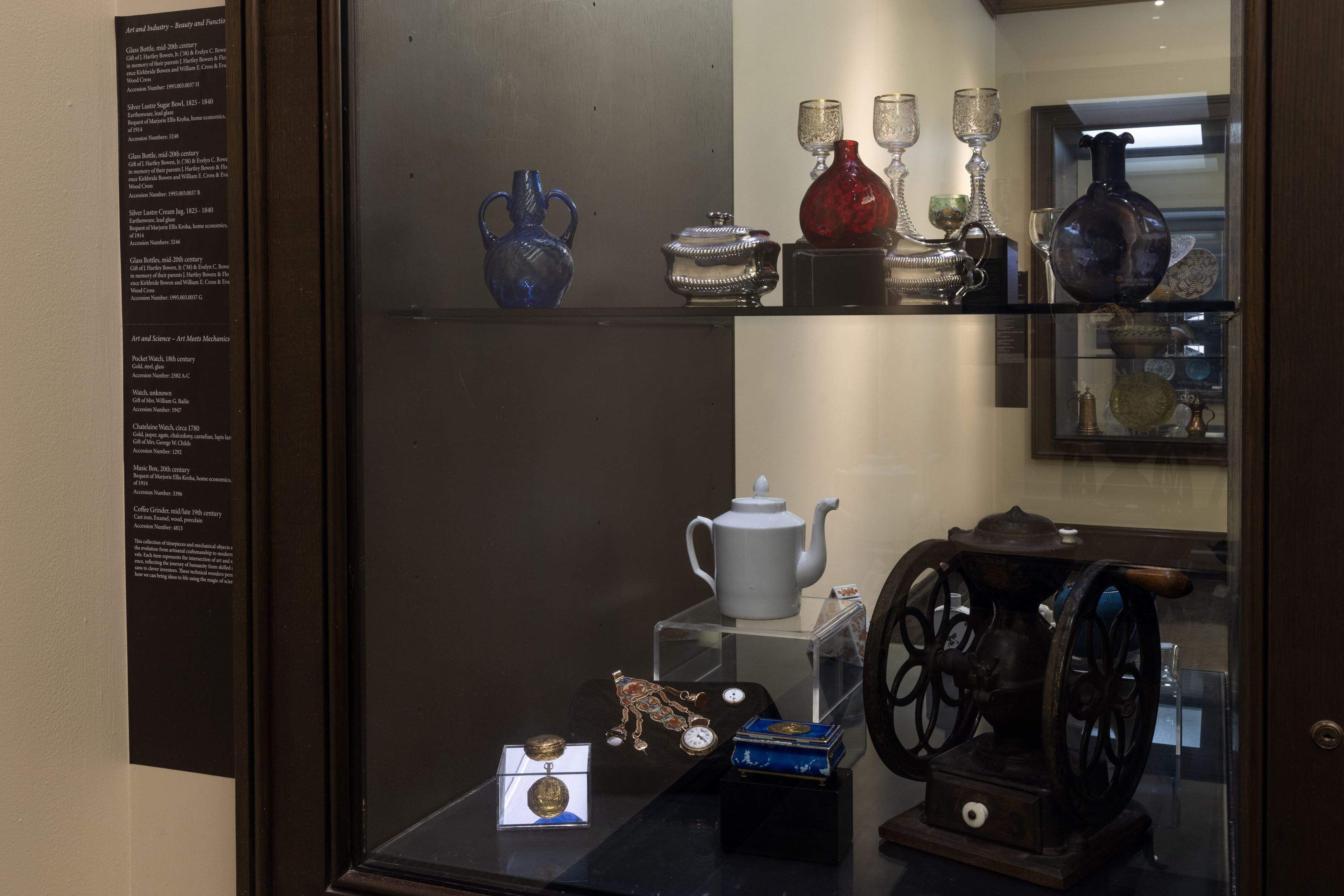 Watches and other household objects in a glass display case.