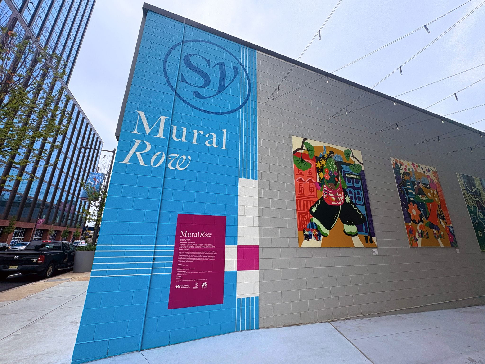 A wall with the text "Mural Row" next to a building