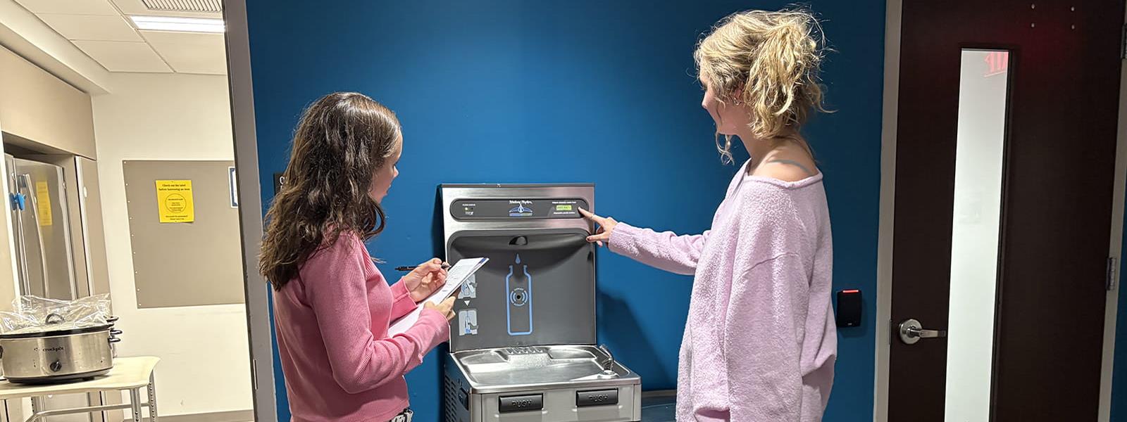 Lakin Casey, left, president of EcoReps, and Lila Woods, EcoRep student, at one of the hydration stations on the University City Campus. Photo credit: Bo Solomon.