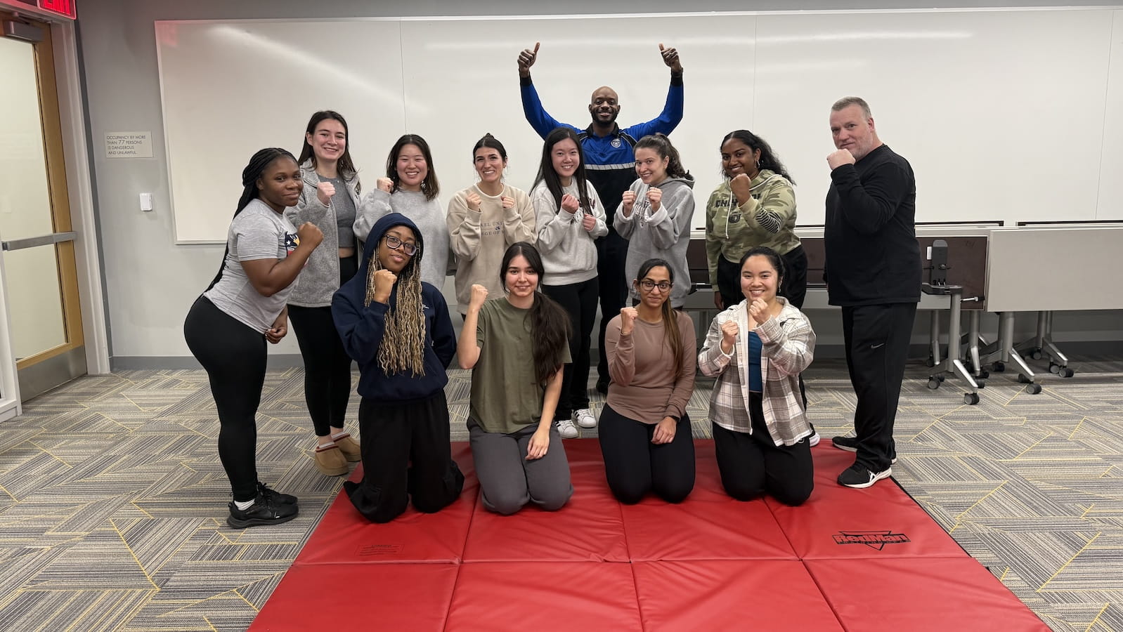 Students and a public safety officers smiling on a red mat.