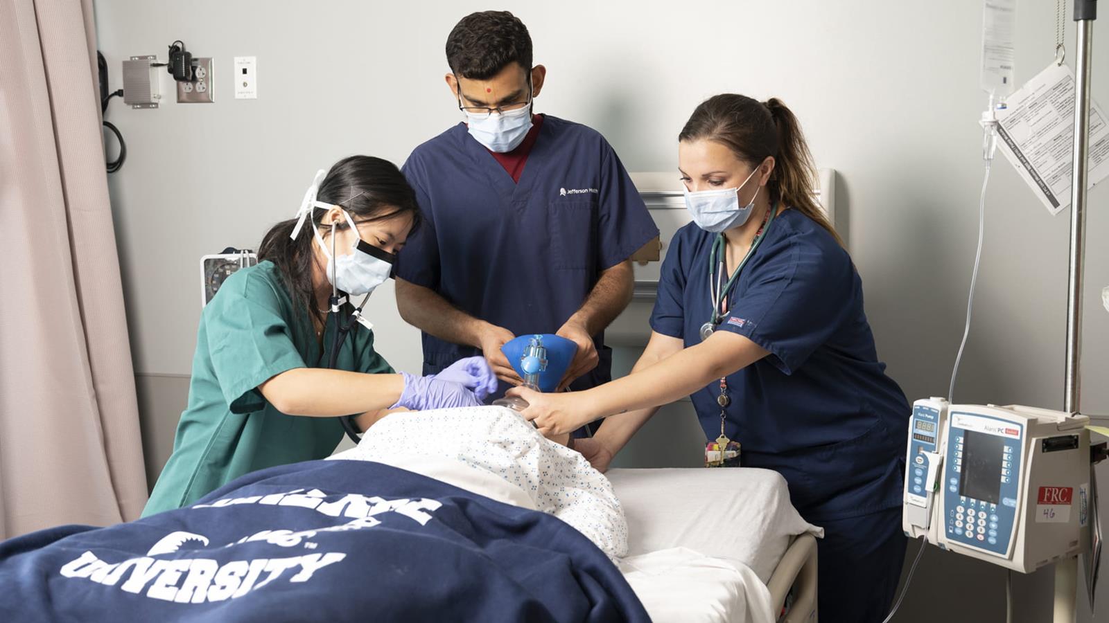 3 nursing students tend to a dummy patient in a simulation lab
