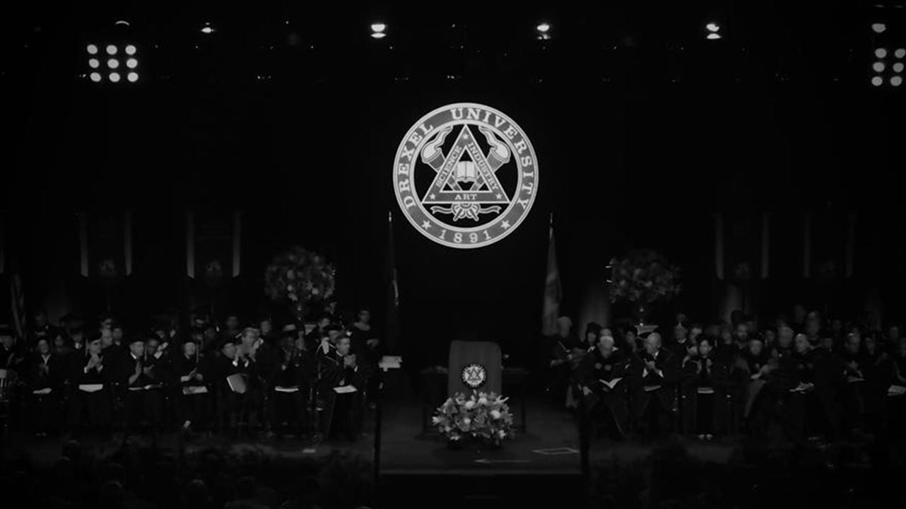 People on a stage at graduation with a podium and Drexel seal