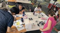 Young Dragons campers building their own robots at a table.
