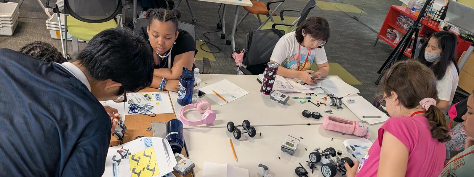 Young Dragons campers building their own robots at a table.