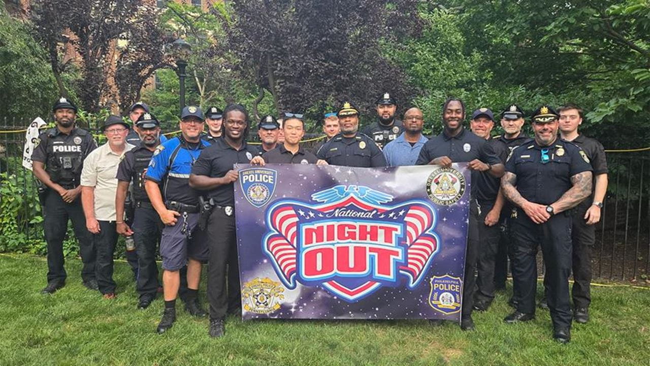 Drexel Public Safety officers holding a National Night Out sign outside.