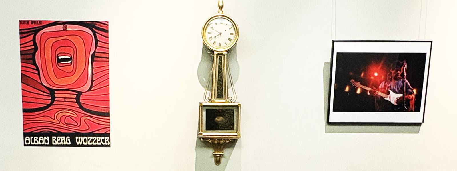 A red Polish poster, a clock and a photograph of Jimi Hendrix on a wall.