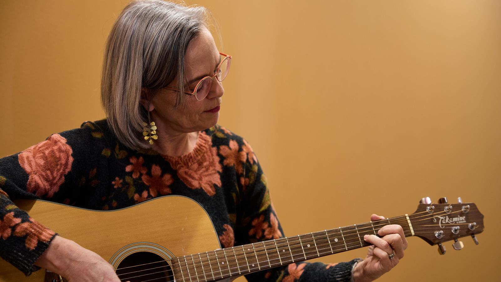 a woman plays an acoustic guitar