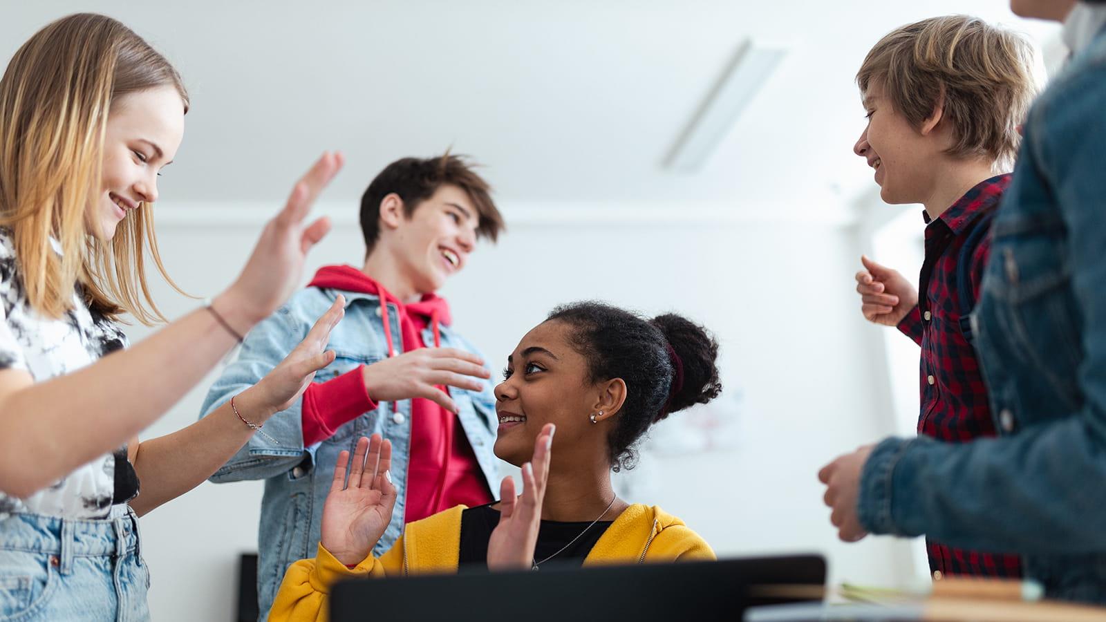 Group of adolescents interacting with each other in a classroom 