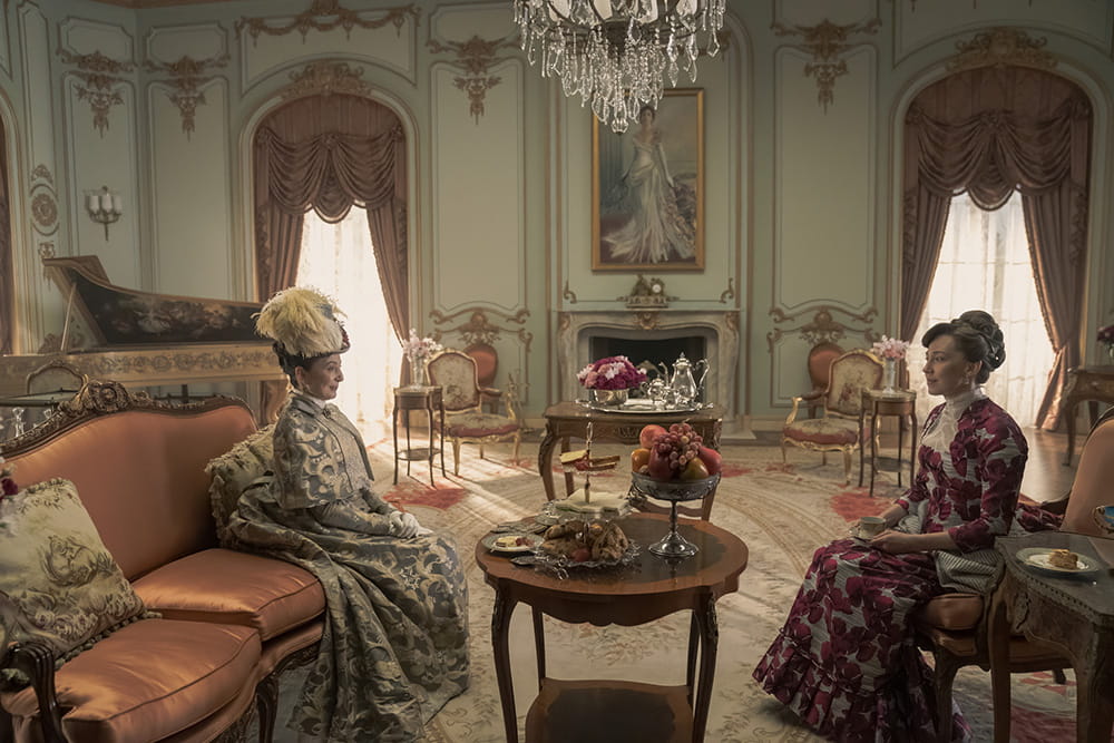 Carrie Coon and Donna Murphy from a scene in "The Gilded Age" sitting on couches in a luxurious sitting room.