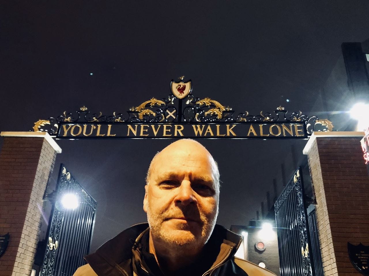 Eric Zillner standing beneath the "You'll Never Walk Alone" sign proudly displayed upon entering Liverpool Football Club’s Anfield Stadium, 