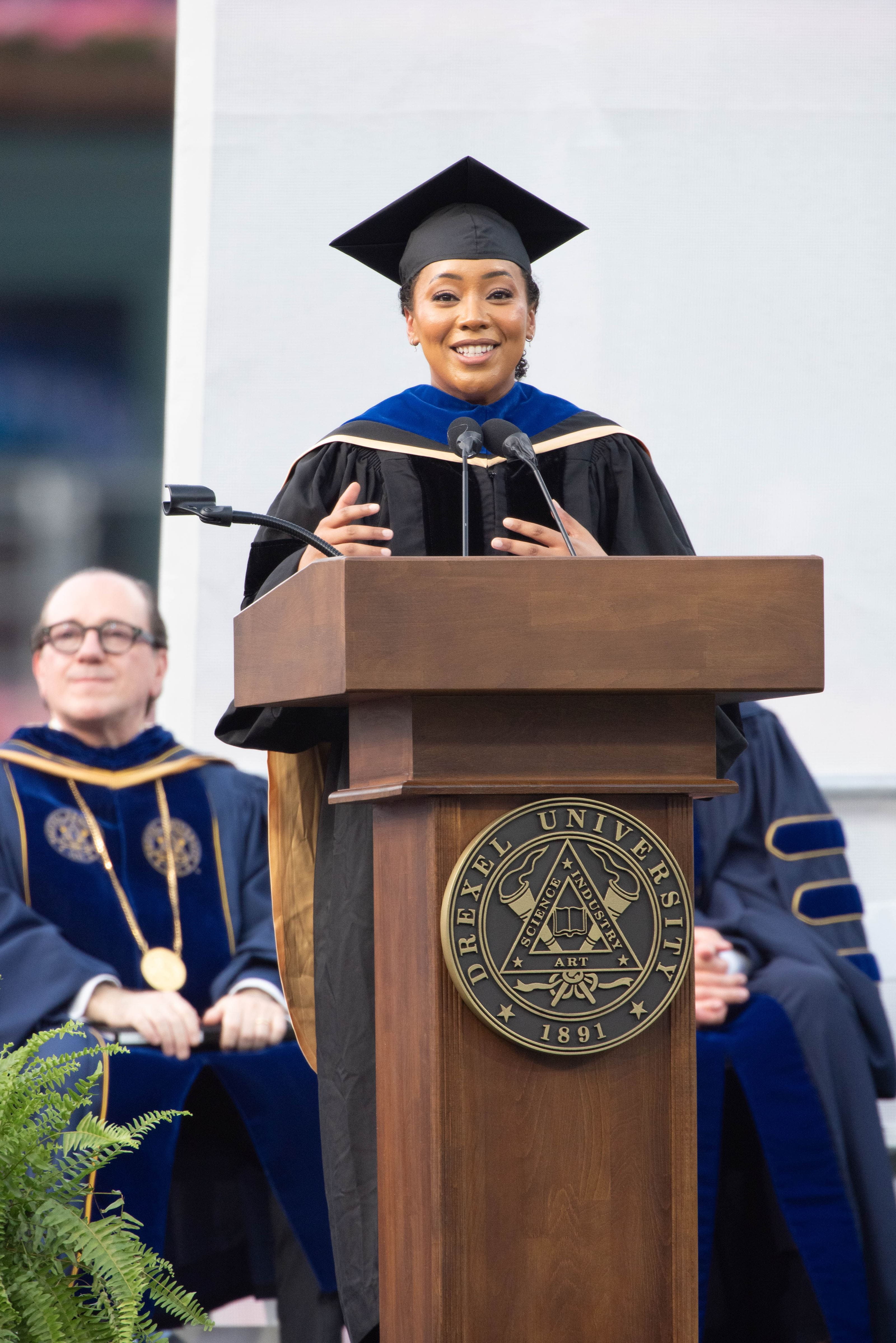 Moogega Cooper speaking at a podium for Drexel's Commencement.