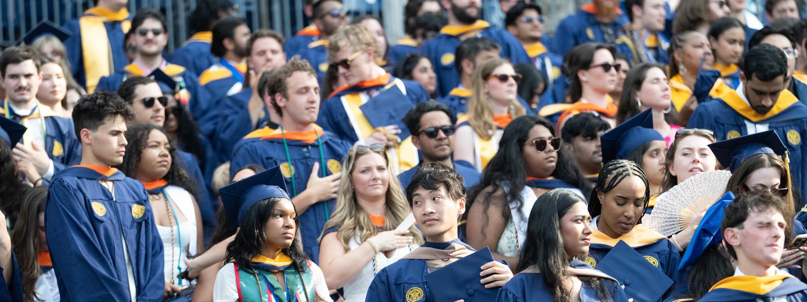 A photo of the crowd of graduates in blue Commencement gowns