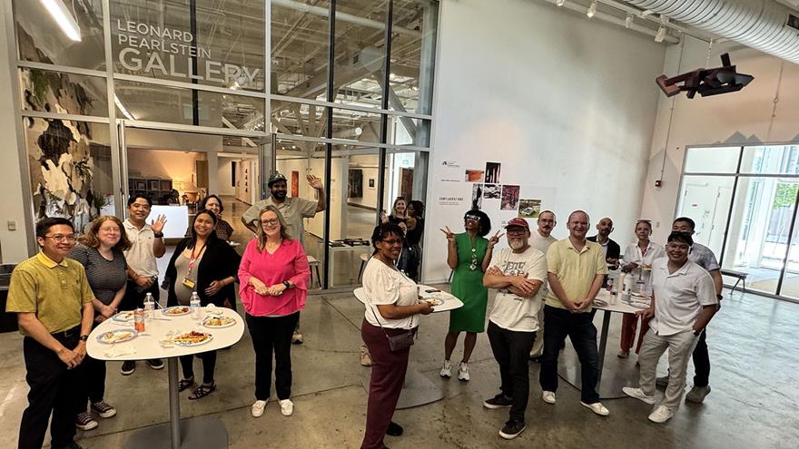 A group of people at tables outside the Leonard Pearlstein Gallery