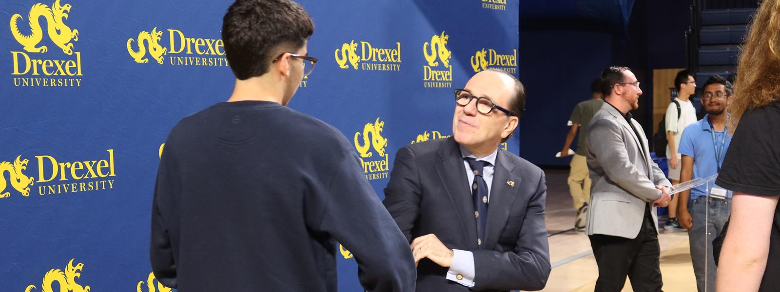 Merlo shakes hands with student