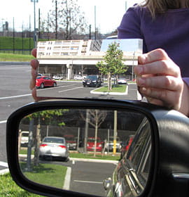 A side-by-side comparison of a standard flat driver's side mirror with the mirror Hicks designed, which has a much wider field of view and minimal image distortion