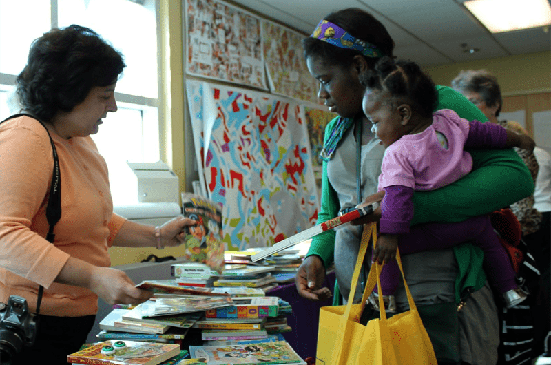 A mother and child receive free children's books at 11th Street Loves to Read Day.