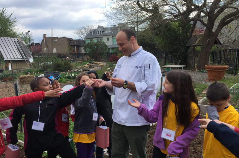 Chef Charles B. Ziccardi, assistant teaching professor of Culinary Arts at Drexel, showing children garden-fresh ingredients during Inspire a Child to Dream Day.