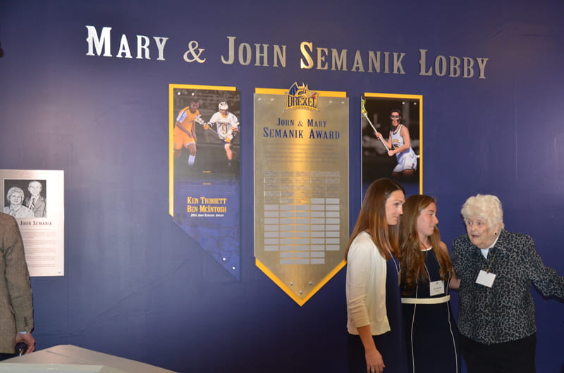Mary Semanik, far right, in the lobby newly dedicated to her and her husband, John, speaking with former women's lacrosse player Amanda Norcini (center) and the Mary Semanik Head Coach of Women's Lacrosse, Hannah Rudloff (left).