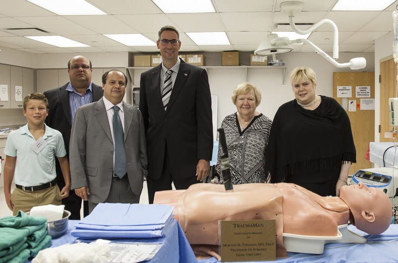 Scott Lind, MD, center in black suit, with Morton Perlman's family and the TraumaMan training mannequin named for him.