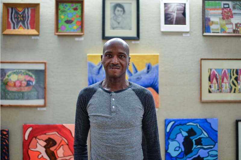 Project HOME alumnus Gerald Halley stands in front of his artwork.