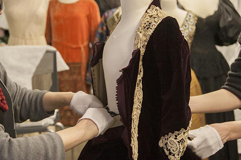 Working on a mannequin for Immortal Beauty: Highlights from the Robert and Penny Fox Historic Costume Collection. Photo by Michael J. Shepherd.