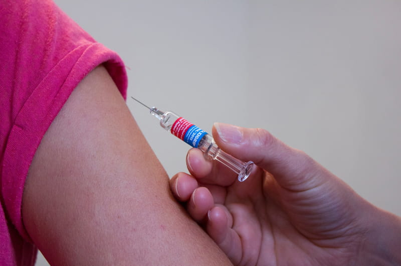 An arm being given an immunization through a needle.