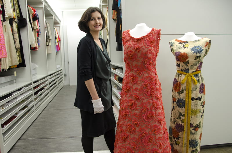 Clare Sauro, curator of the Fox Historic Costume Collection, stands next to a coral-encrusted Hubert de Givenchy couture gown worn by Grace Kelly.
