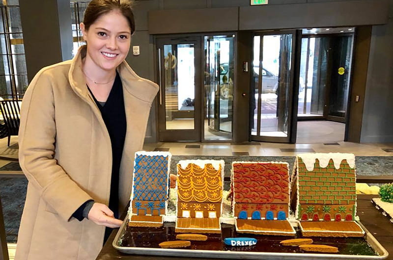 Nora Vaughan stands with the finished Boathouse Row gingerbread house display at the Logan Hotel.