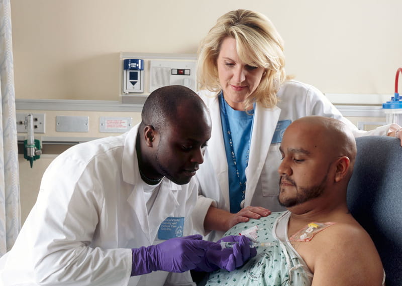 A pair of doctors treating a patient with chemotherapy.
