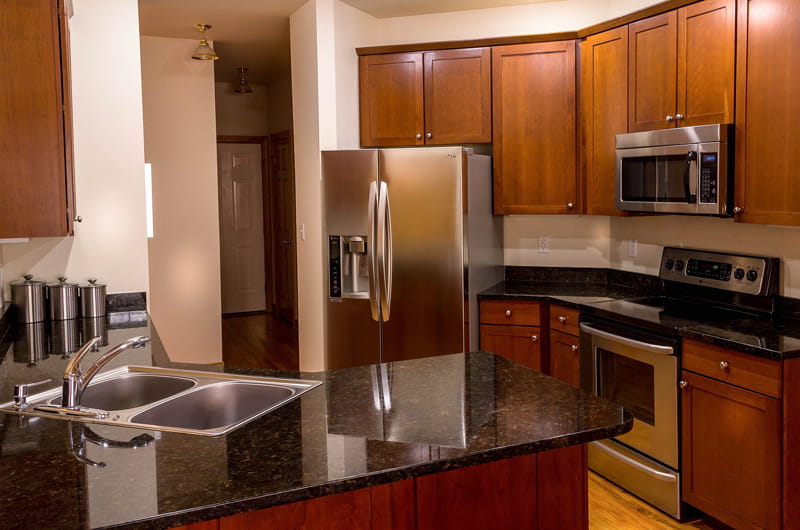 Kitchen with black countertops, sink, oven, microwave and refrigerator.