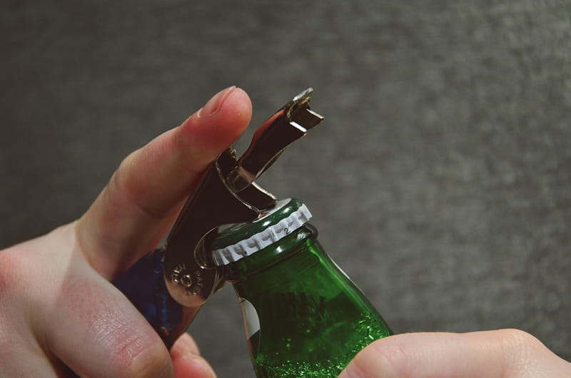 Hands opening a beer bottle