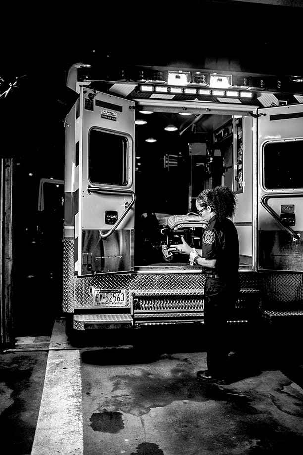 A medic behind her ambulance looking at some paperwork.
