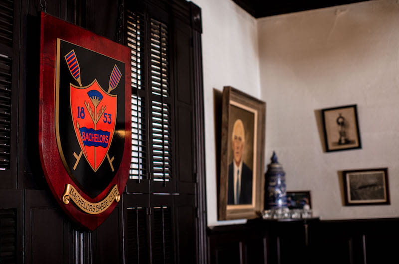 The walls of the Button are filled with hanging memorabilia, like a plaque with the Bachelors Barge Club crest, left, and a painting of Olympic gold medalist and Bachelors Barge Club president W.E. Garrett Gilmore, or "Loft," right. 