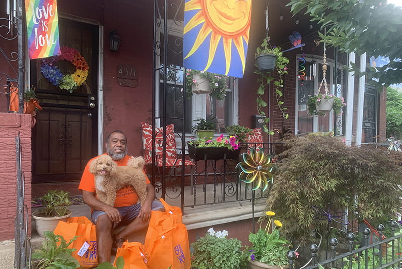 Jeffrey Jordan on his porch with his dog, Justice, surrounded by supplies to distribute to the West Philadelphia Promise Neighborhood. Photo courtesy Jeffrey Jordan.