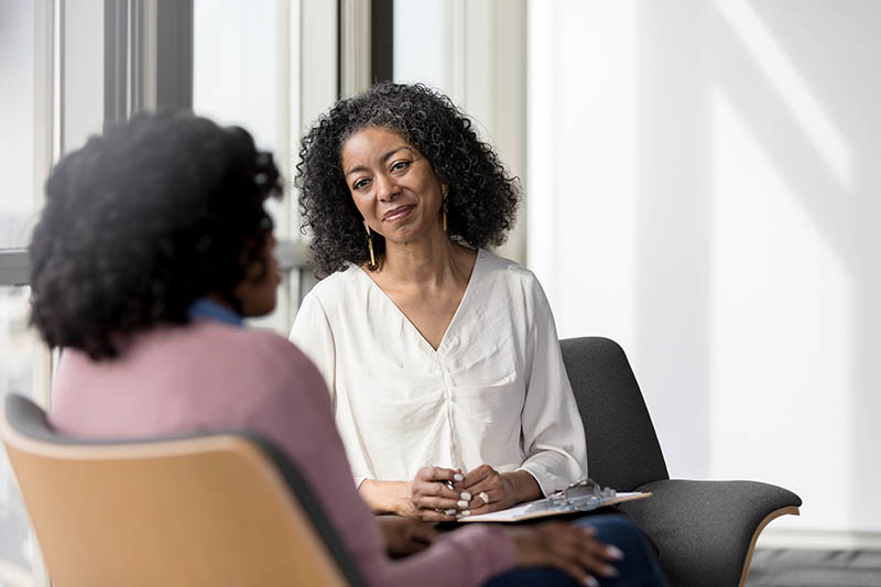 Mature counselor listens compassionately to unrecognizable female client.