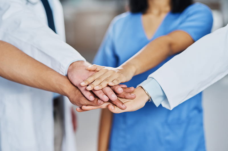 Closeup shot of a group of medical practitioners joining their hands together in a huddle