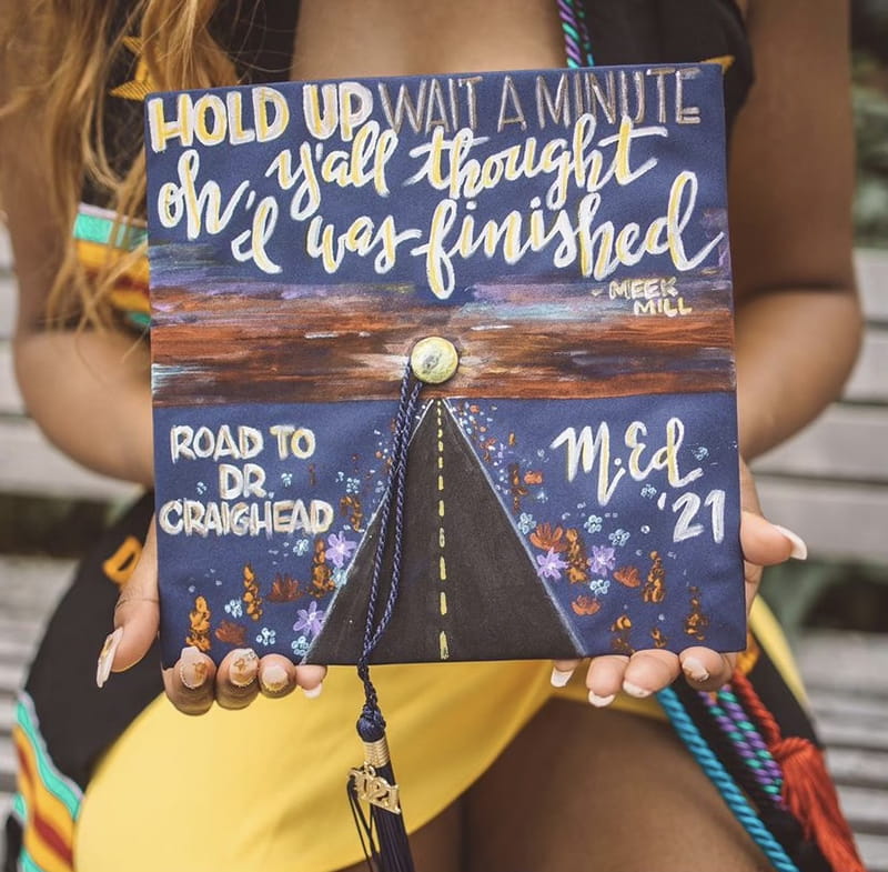 A commencement cap with a road design and a Meek Mill quote.