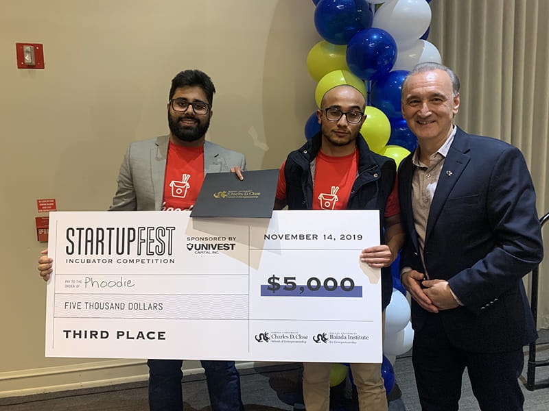 In this pre-pandemic photo, Chuck Sacco (left), associate dean for strategy and innovation and director of the Baiada Institute for Entrepreneurship, presents prize winnings to the founders of startup company Phoodie.