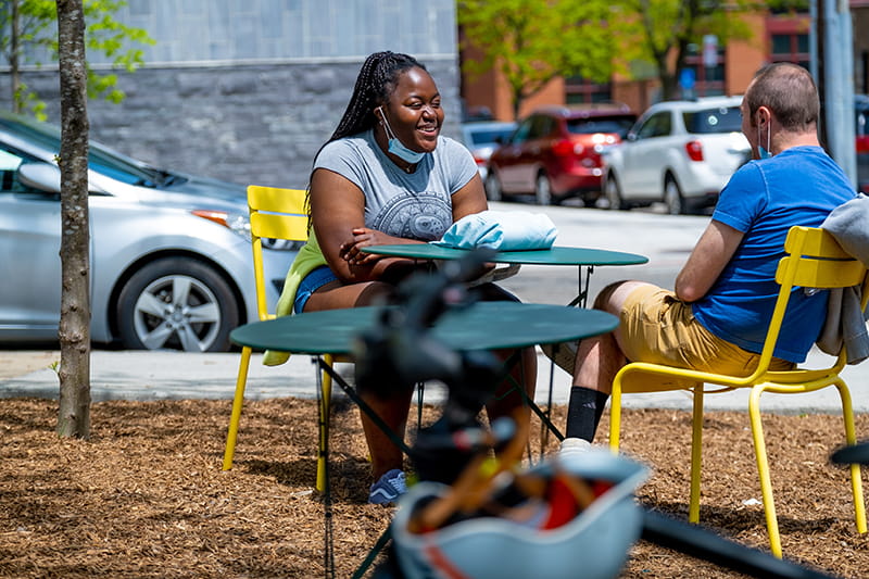 Two Drexel students sit at a table outside.
