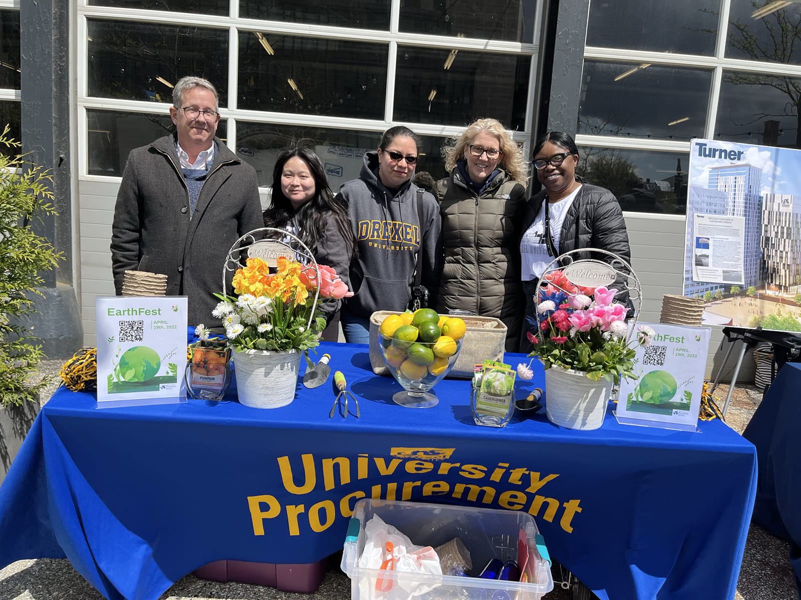 Members of University Procurement stand behind a table of flowers.