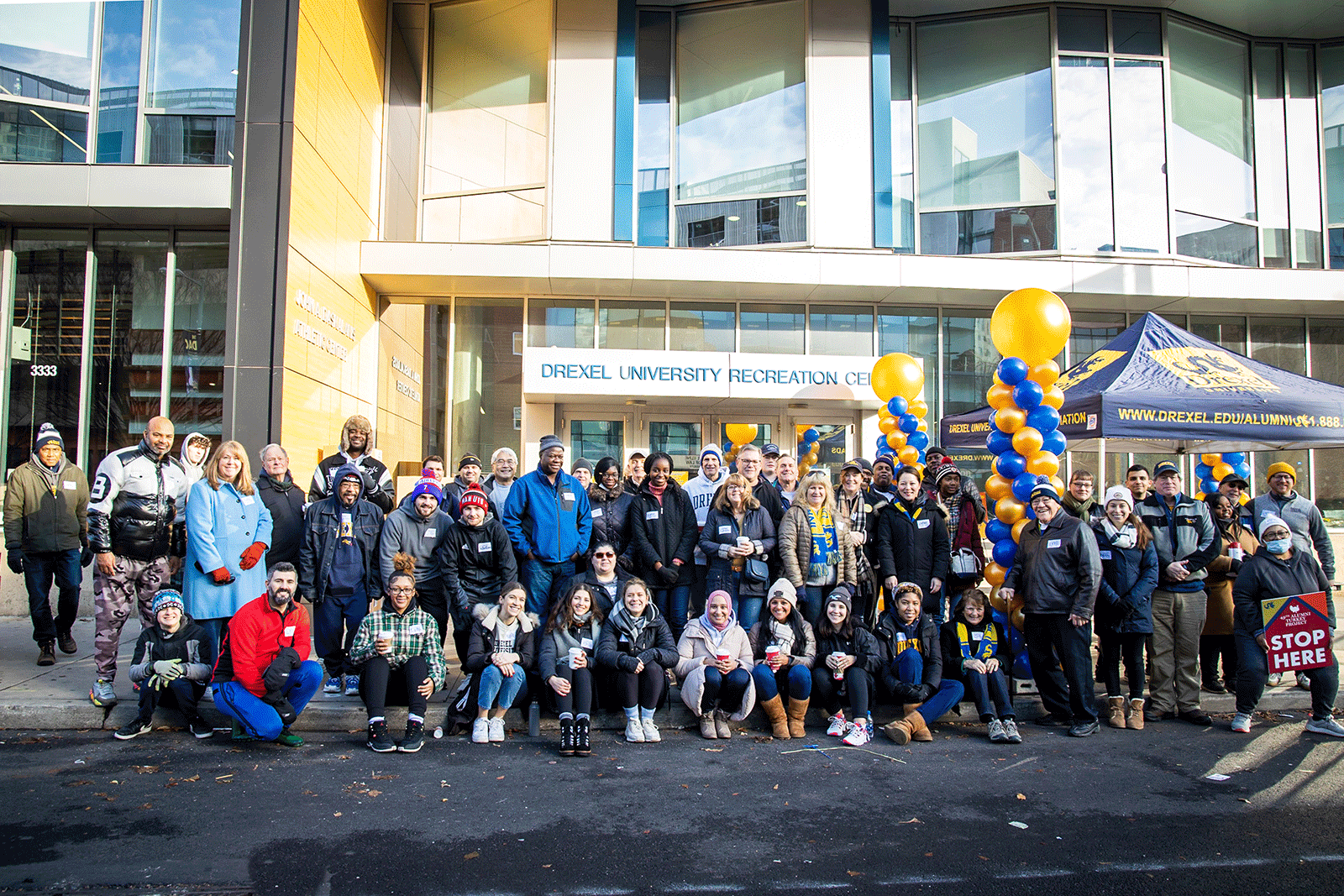 A gift. Volunteers from the packing day for the Active-Duty Military Care Package Drive on Dec. 2. A large group of alumni and volunteers in front of the Drexel Recreation Center during the turkey distribution day on Dec. 19.