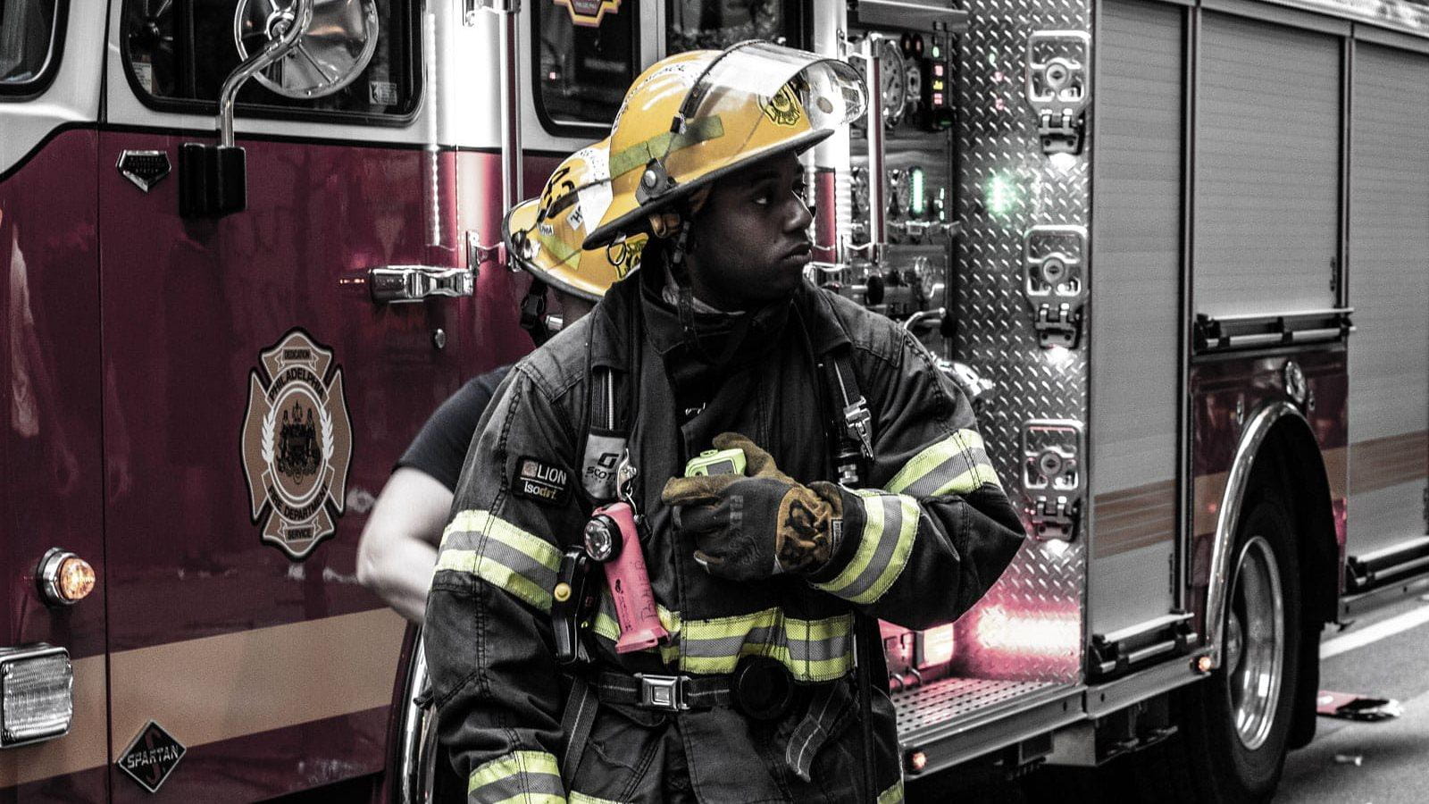 A firefighter stands in front of a fire truck.