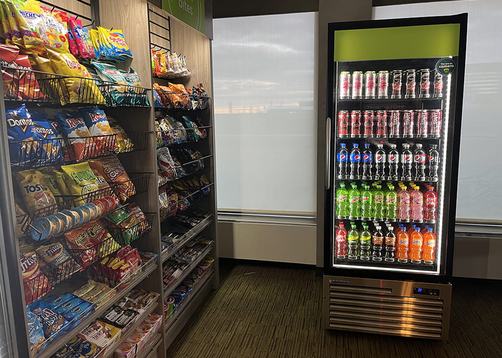 A close look at an area of refrigerated cases and a wall of snacks for purchase.