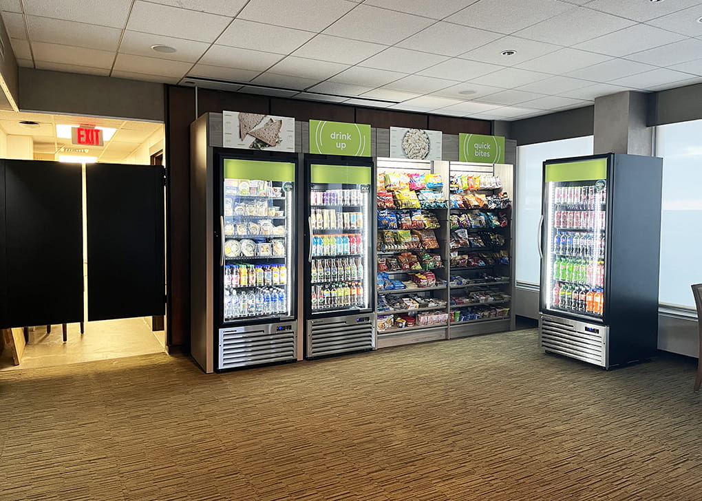 An area of refrigerated cases and a wall of snacks for purchase.