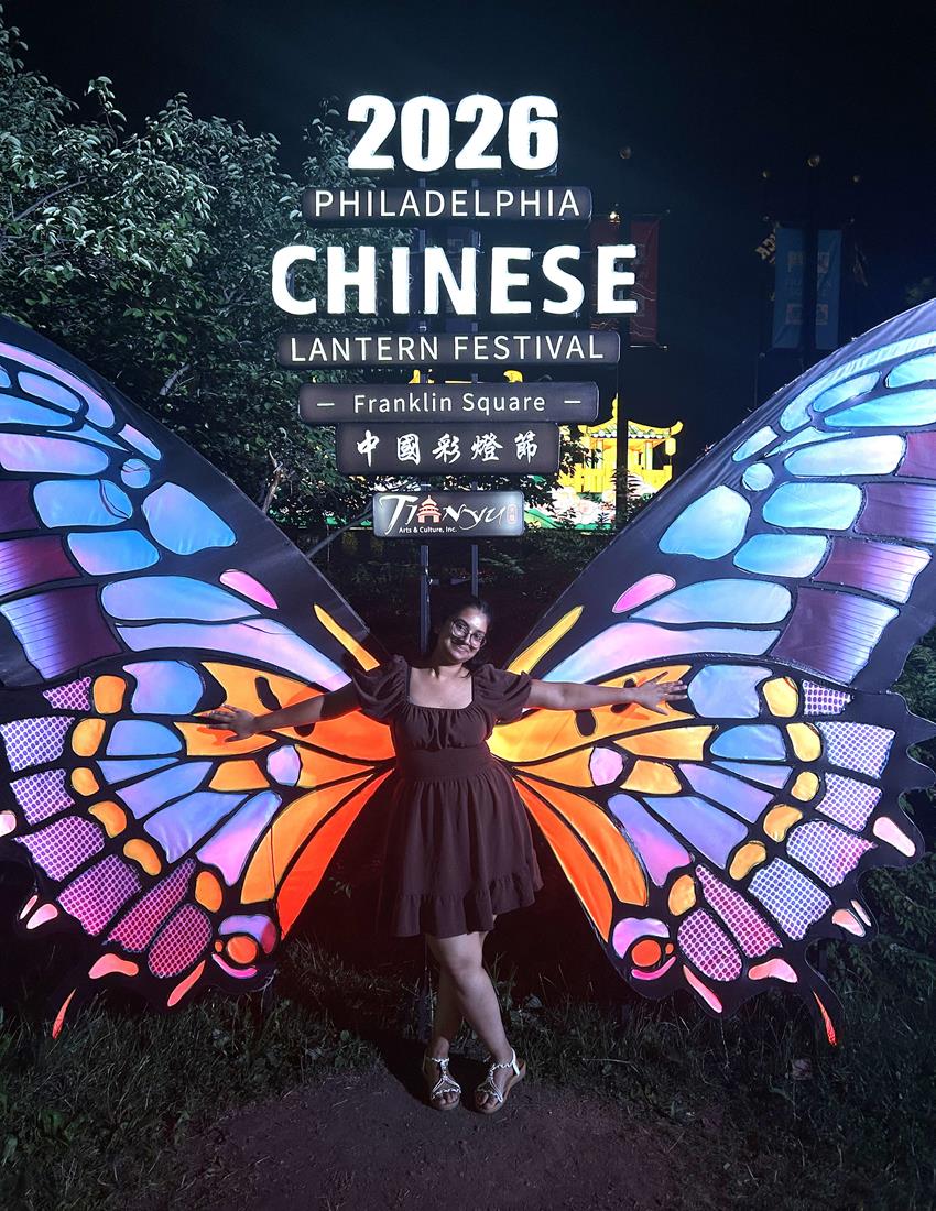 A student stands in front of large butterfly wings at the Chinese Lantern Festival.