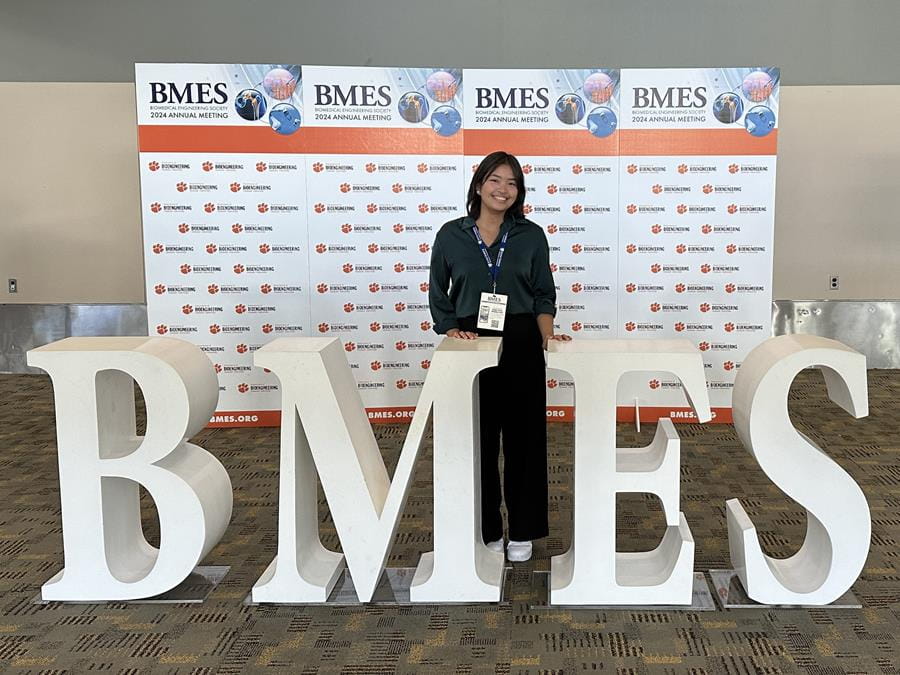 A student poses with a conference sign