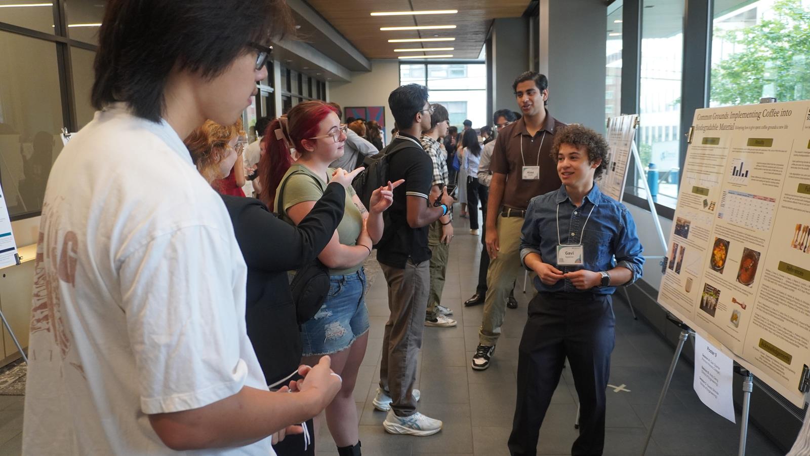 A STAR Scholar presents his research poster to a group of students.