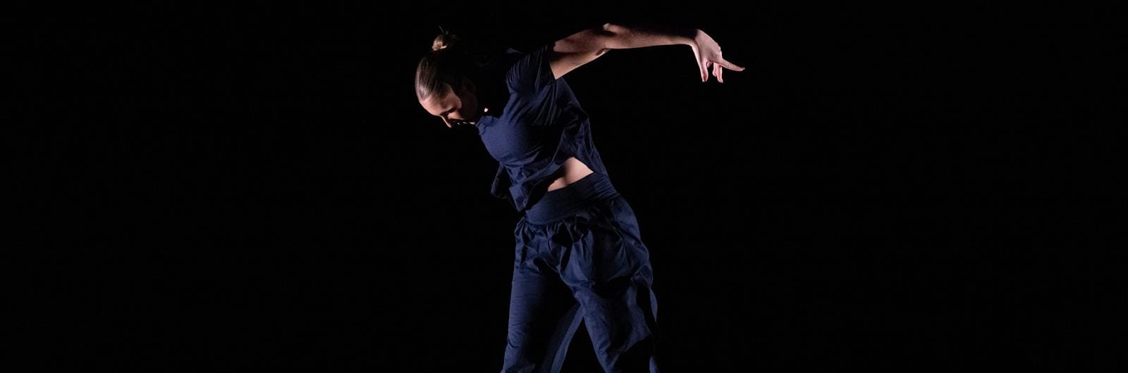 Dancer jumps against a dark background