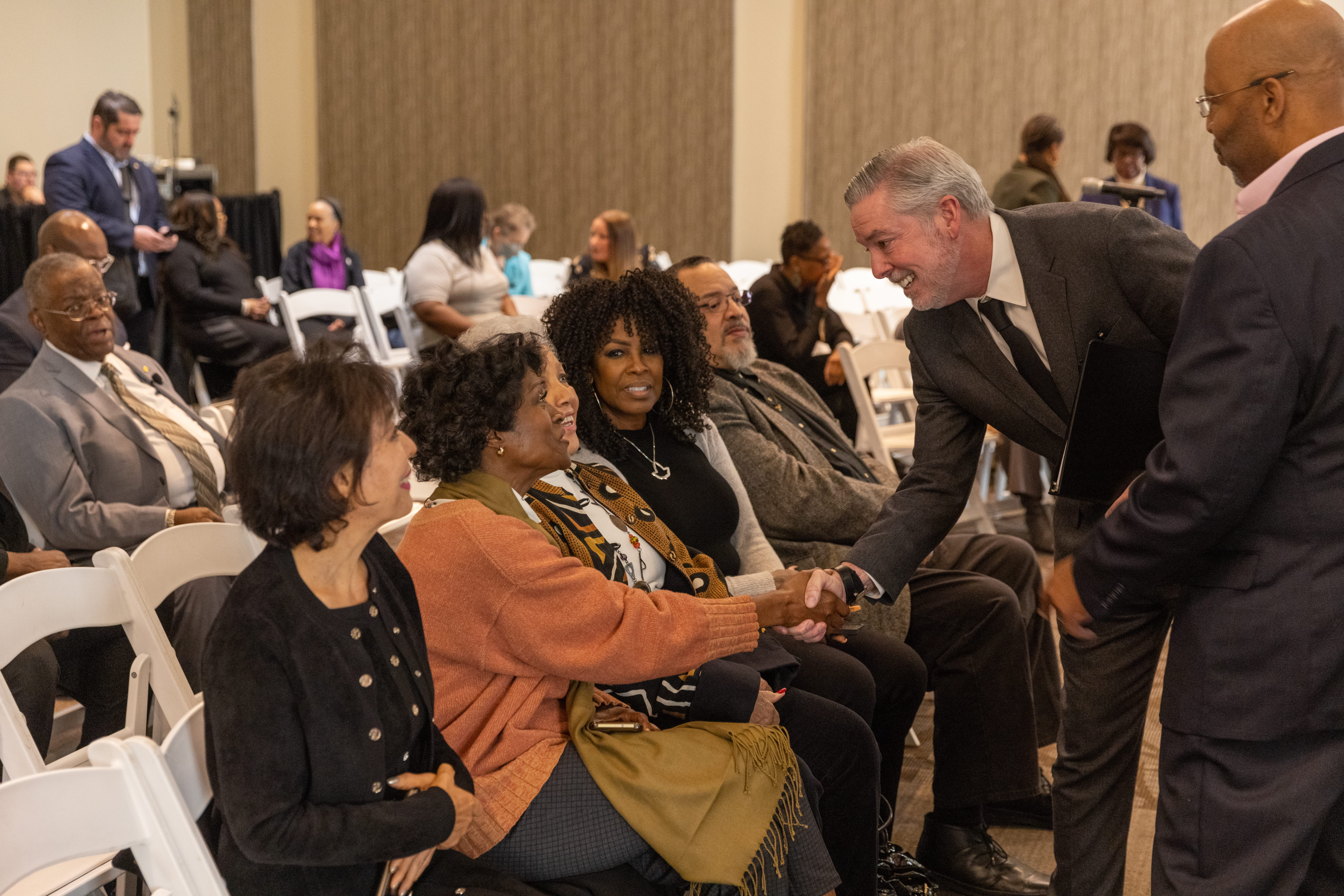 President John Fry shaking the hand of a woman in the audience.