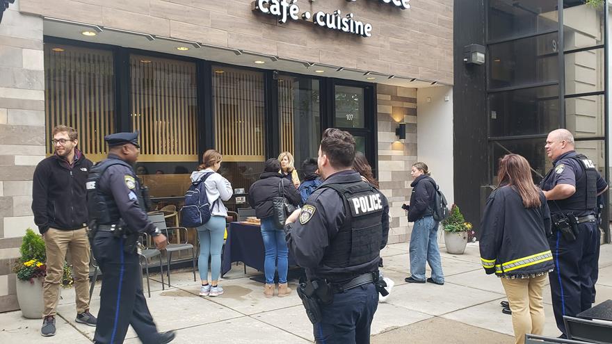 Police officers and community residents standing and getting coffee on a sidewalk